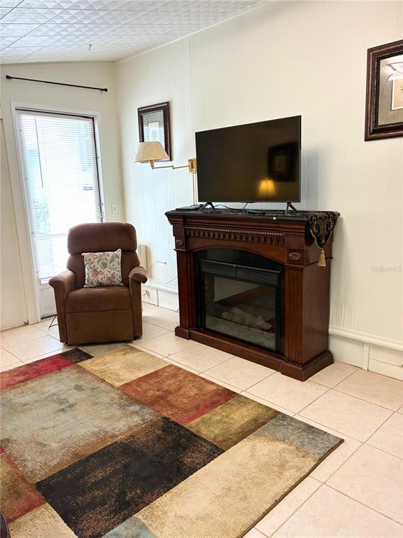 A living room features a brown recliner, a fireplace with a television, and tiled flooring — 4981 PEBBLE BEACH AVENUE, SARASOTA, FL