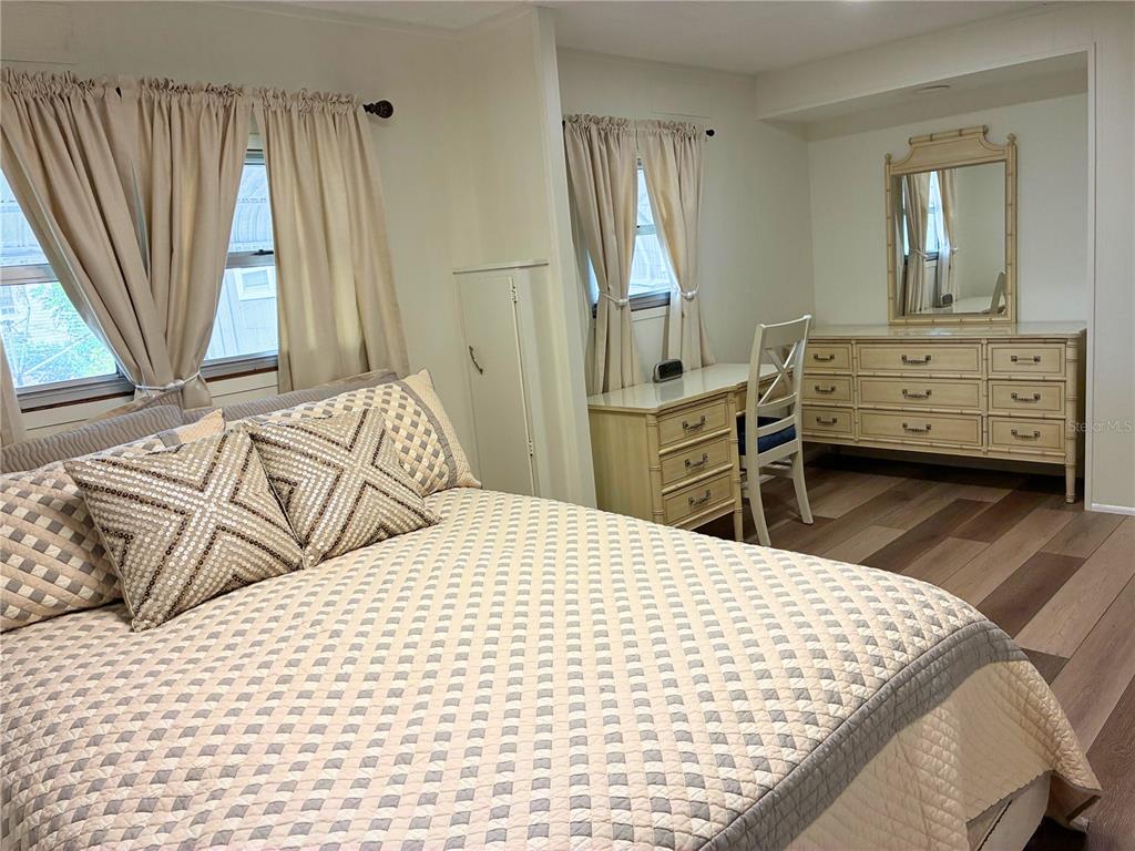 A bedroom features a bed with patterned pillows, a desk, a dresser, and two windows — 4981 PEBBLE BEACH AVENUE, SARASOTA, FL