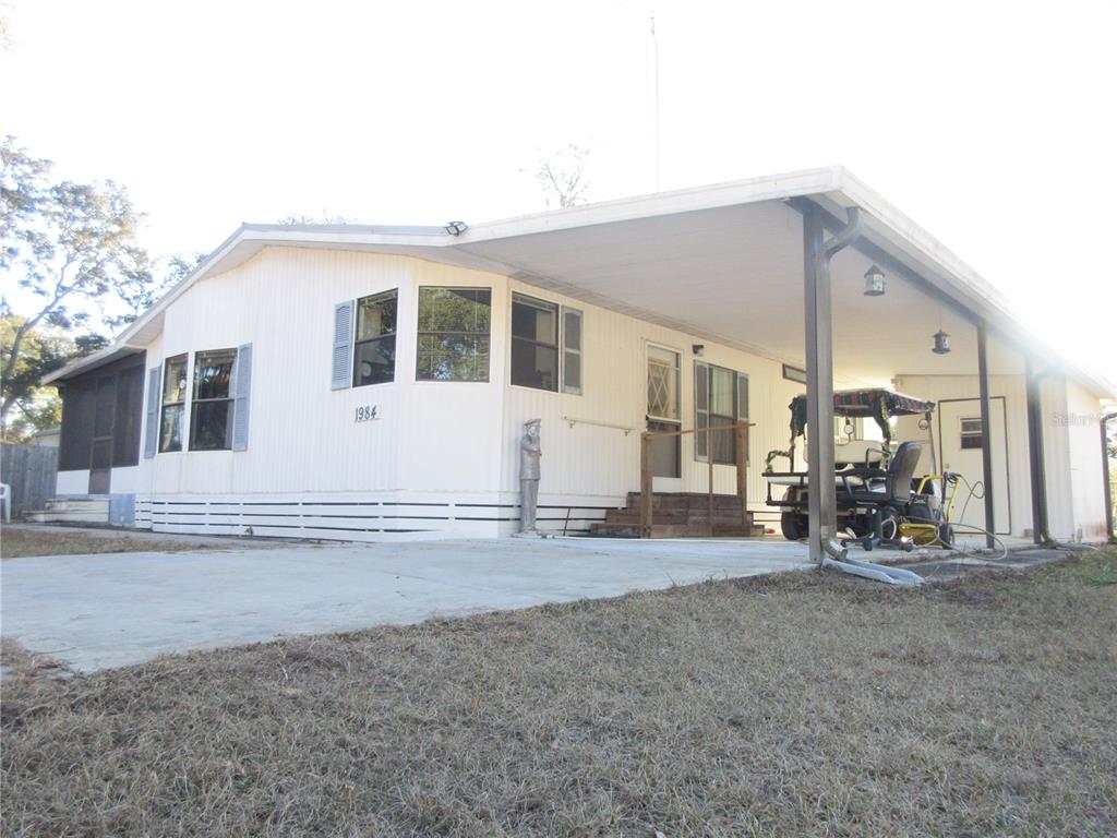 A single-story manufactured home with white siding, a large carport, and a concrete driveway — 1984 SE 171ST COURT, SILVER SPRINGS, FL