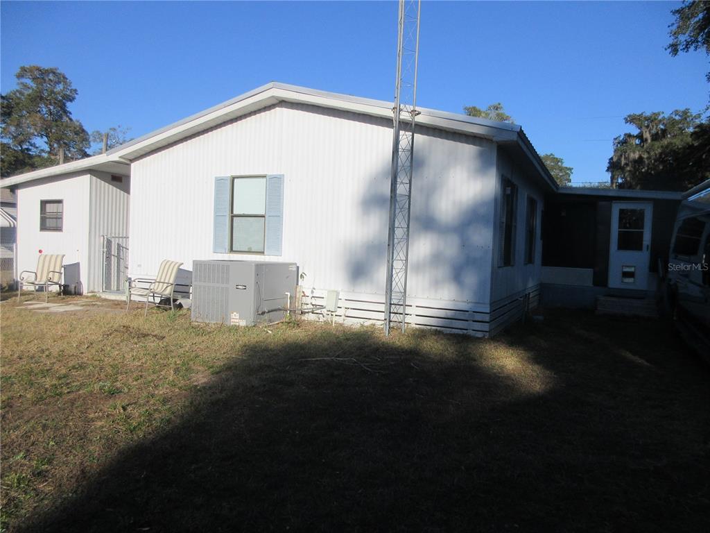 The exterior of a white mobile home features a metal antenna tower and an air conditioner — 1984 SE 171ST COURT, SILVER SPRINGS, FL