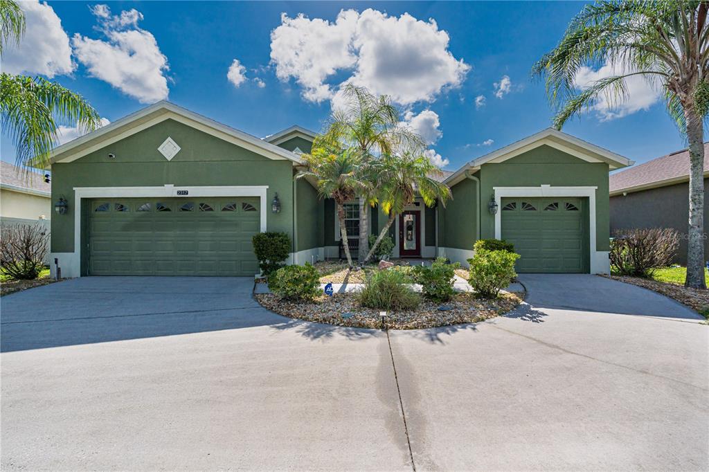 A green single-story house features a three-car garage and a central entrance with palm trees — 2317 CROSSTON CIRCLE, ORLANDO, FL