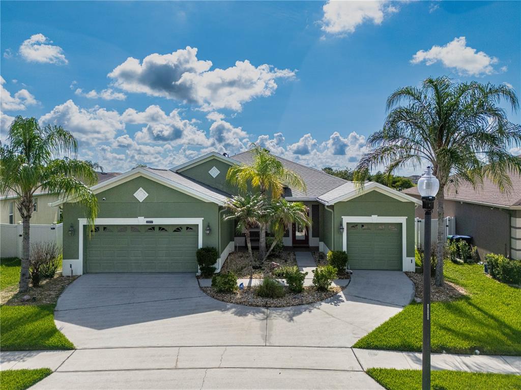 A green single-story house with a three-car garage and palm trees in the front yard — 2317 CROSSTON CIRCLE, ORLANDO, FL