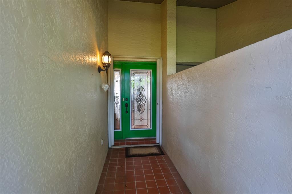 A green front door with decorative glass panels sits at the end of a tiled entryway — 2611 LANCASTER DRIVE UNIT 33, SUN CITY CENTER, FL