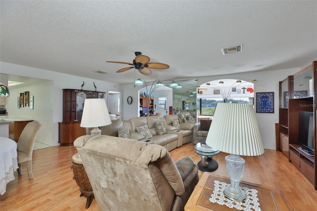 A living room features light wood flooring, a beige sectional sofa, and a ceiling fan — 2611 LANCASTER DRIVE UNIT 33, SUN CITY CENTER, FL