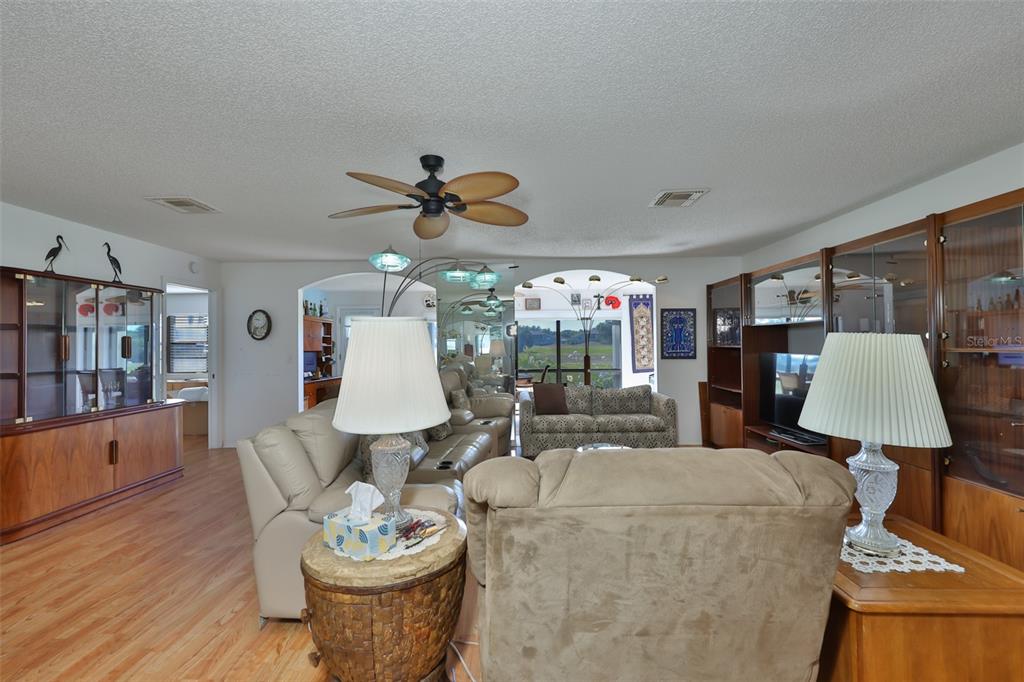 A living room features wood flooring, a ceiling fan, and large wooden display cabinets — 2611 LANCASTER DRIVE UNIT 33, SUN CITY CENTER, FL