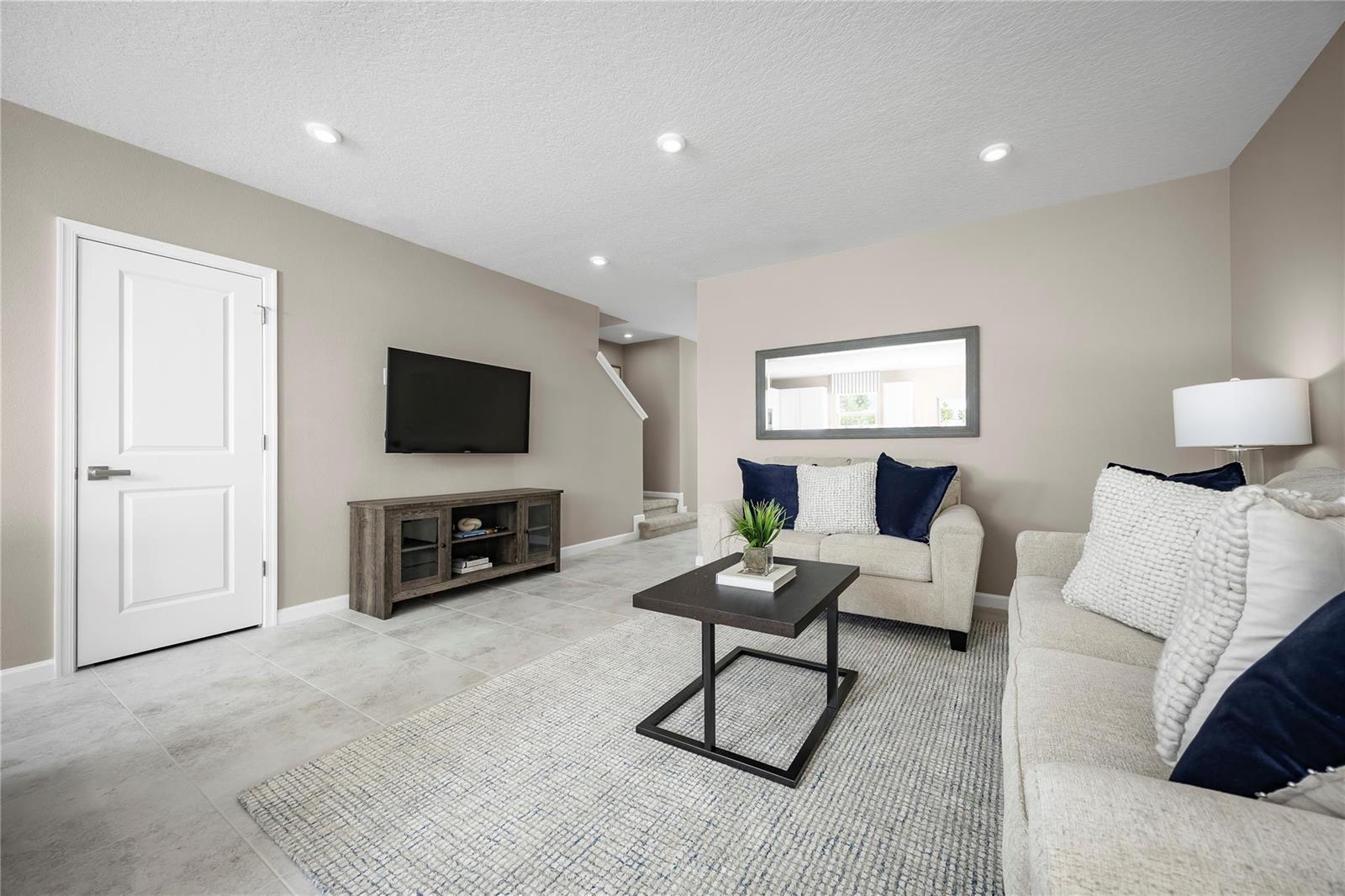 A living room features light tile floors, a wall-mounted television, and neutral-toned furniture — PORT ST. LUCIE, FL