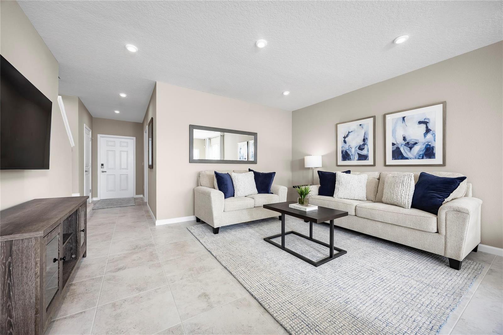 A living room features light tile floors, a neutral sofa set, and a dark wood console — PORT ST. LUCIE, FL