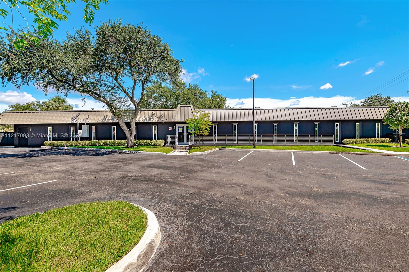 A single-story commercial building with a dark exterior, metal roof, and an adjacent parking lot — 7700 Davie Road Ext, Hollywood FL 33024, HOLLYWOOD, FL