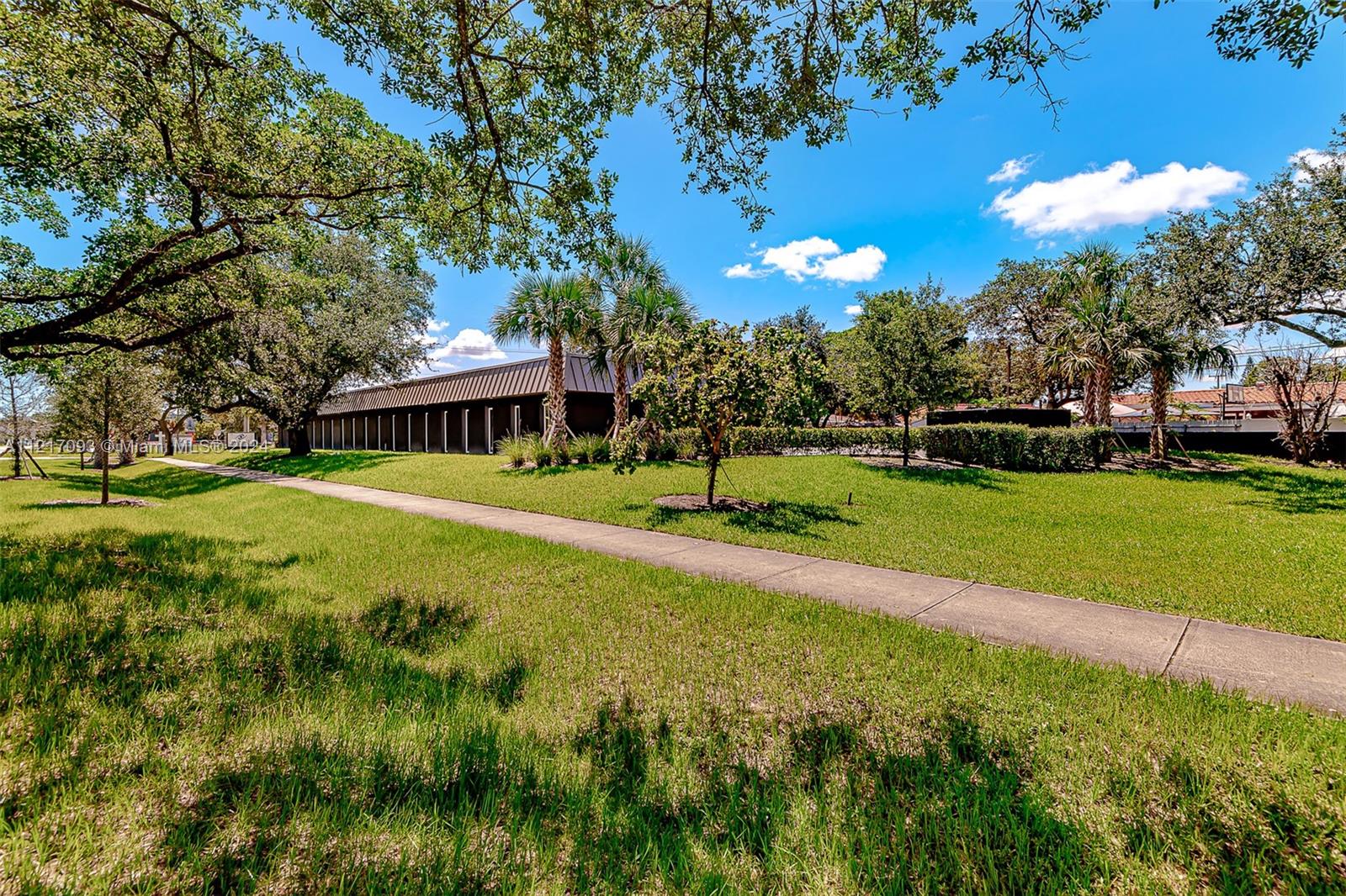 A long, single-story building sits behind a grassy lawn with trees and a sidewalk — 7700 Davie Road Ext, Hollywood FL 33024, HOLLYWOOD, FL