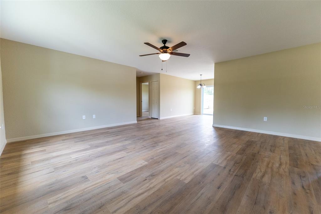 An open-concept living area features light-colored walls, wood-look flooring, and a ceiling fan — 14686 SW 79TH AVENUE ROAD, OCALA, FL