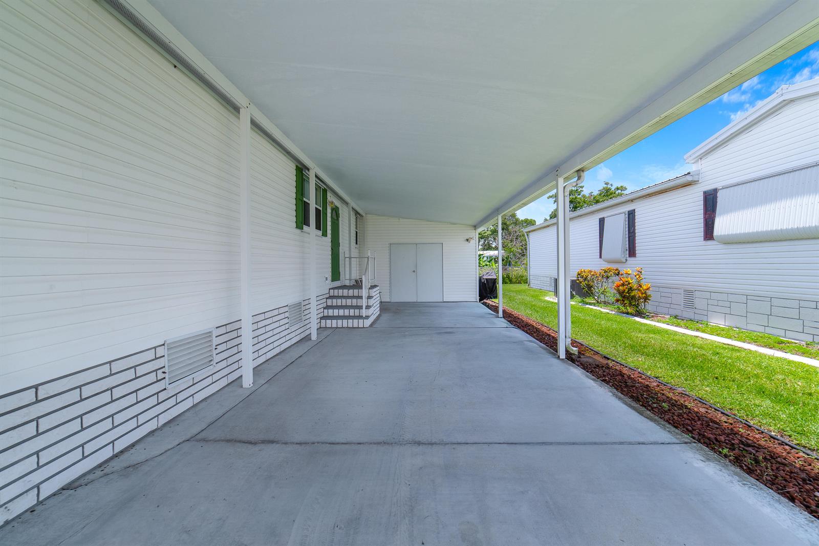 A concrete carport sits between two white mobile homes with a small storage shed — 1651 SW 35th Circle, Okeechobee FL 34974, OKEECHOBEE, FL