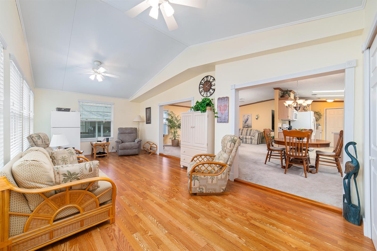 A living room with hardwood floors, wicker furniture, and an opening to a dining area — 1651 SW 35th Circle, Okeechobee FL 34974, OKEECHOBEE, FL