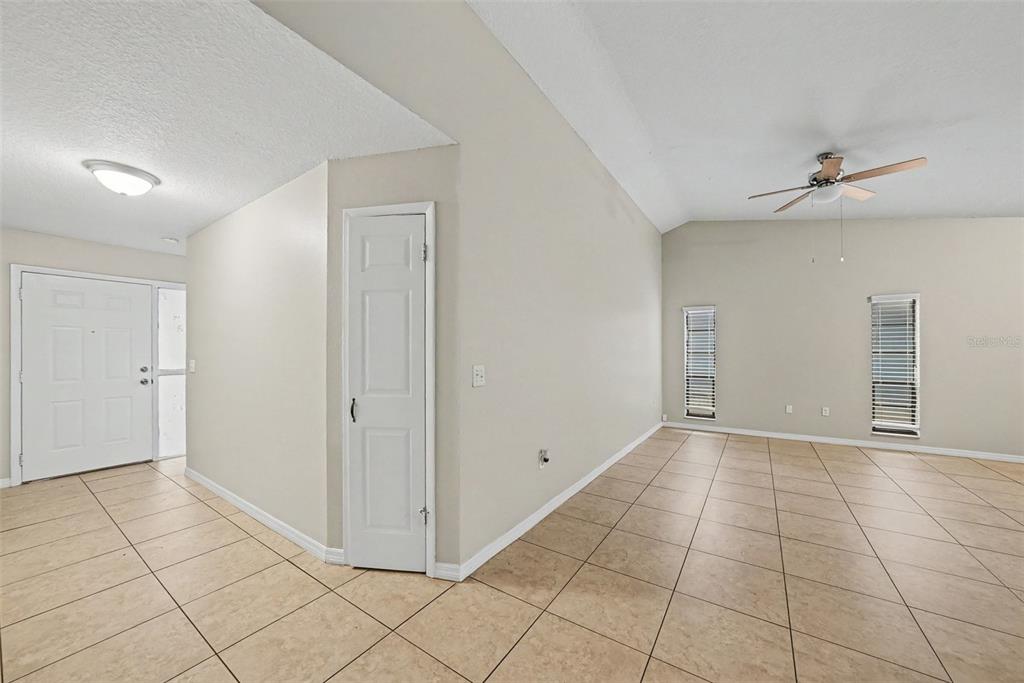 A room with beige tile flooring, a white door, and a ceiling fan — 7623 BRAMBLEWOOD DRIVE, PORT RICHEY, FL