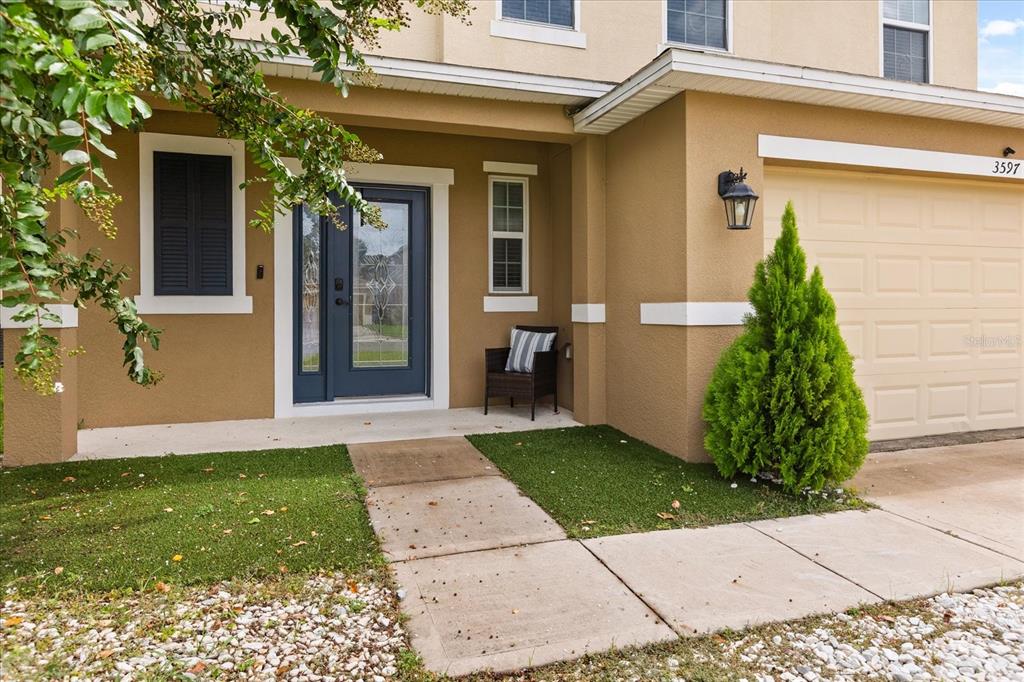 The exterior of a tan house features a dark blue front door and a garage — 3597 UMBRELLA COURT, TAVARES, FL
