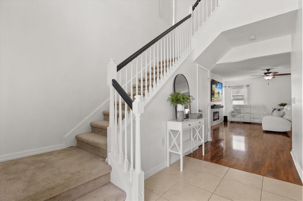 A carpeted staircase with a white railing leads to an upper level near a living area — 3597 UMBRELLA COURT, TAVARES, FL