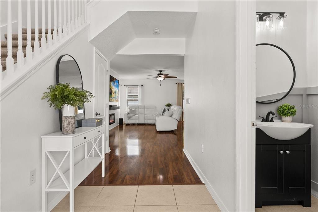 A bright entryway with a white console table leads into a living room with wood floors — 3597 UMBRELLA COURT, TAVARES, FL