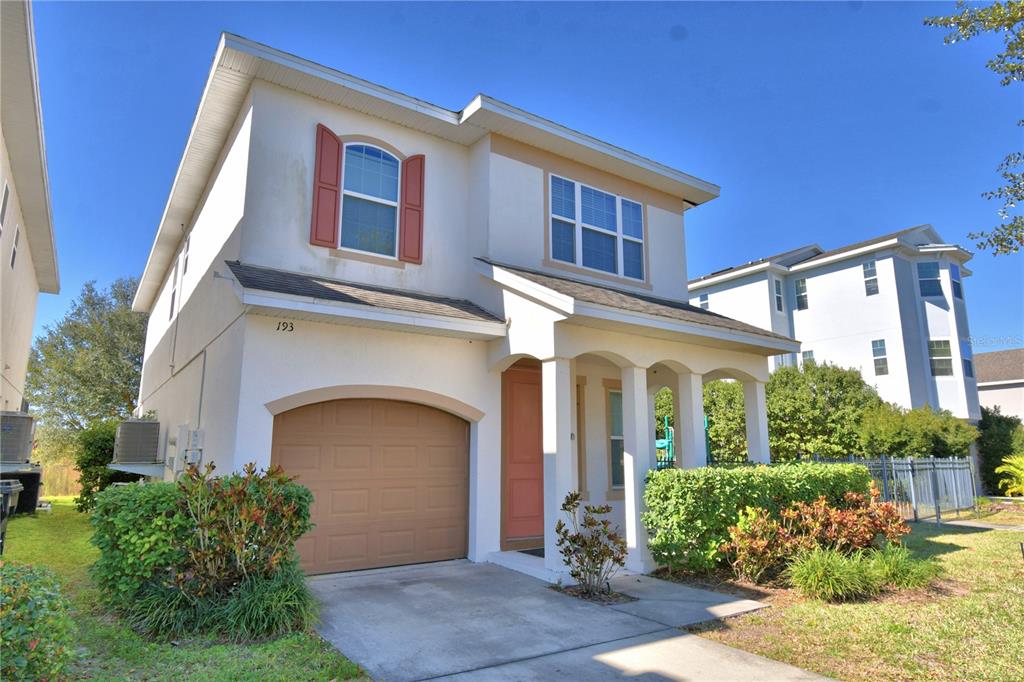 A two-story house with a tan garage, red shutters, and a covered front porch — 193 ABERDEEN STREET, DAVENPORT, FL