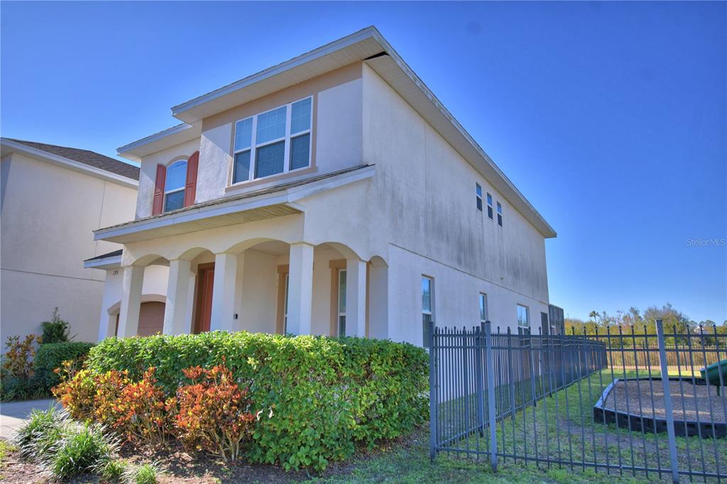 A two-story stucco house features a covered front porch and a black metal fence — 193 ABERDEEN STREET, DAVENPORT, FL