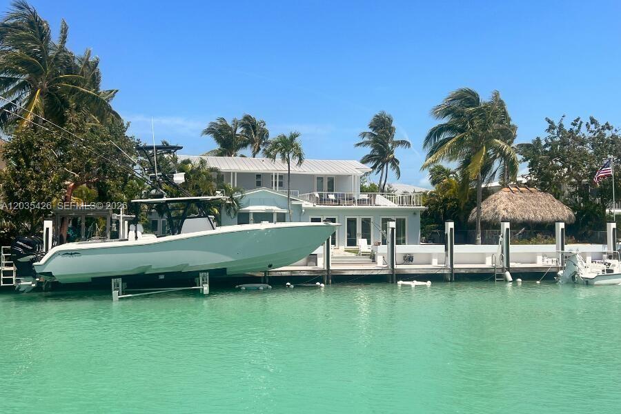 A large white boat is docked in front of a two-story house with palm trees — DUCK, FL