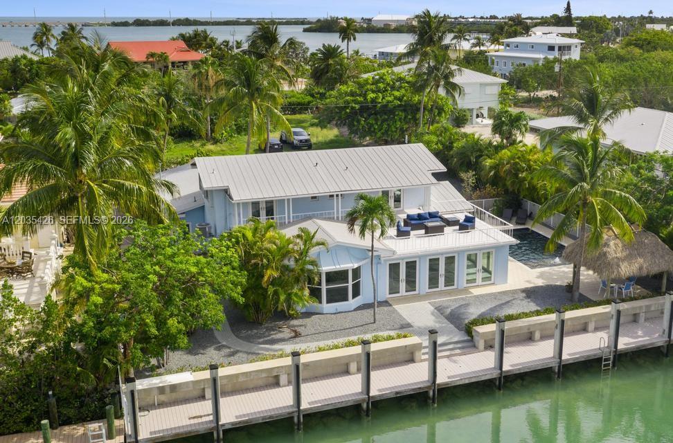 An aerial view of a light blue waterfront house with a dock and swimming pool — DUCK, FL