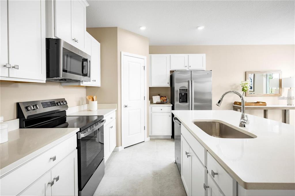 A modern kitchen features white cabinets, stainless steel appliances, and a central island with sink — 2744 GINGER LANE, HAINES CITY, FL