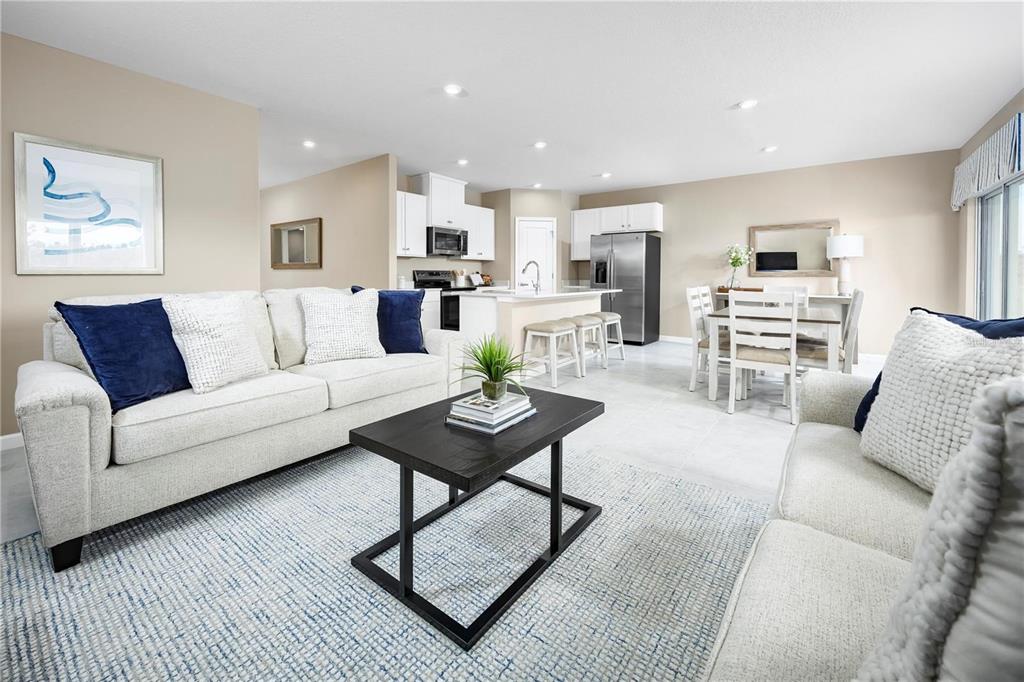 An open-concept living room features a white sofa, a black coffee table, and a kitchen — 2744 GINGER LANE, HAINES CITY, FL