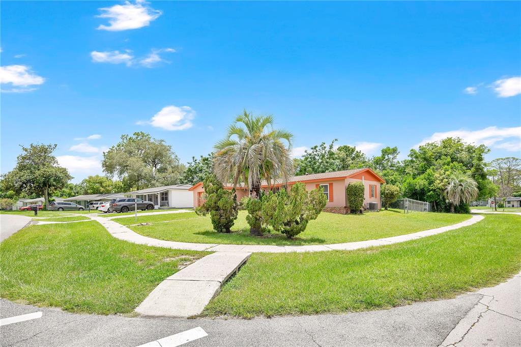A single-story peach-colored house sits on a corner lot with a palm tree and lawn — 1140 COBBLESTONE AVENUE, DELTONA, FL