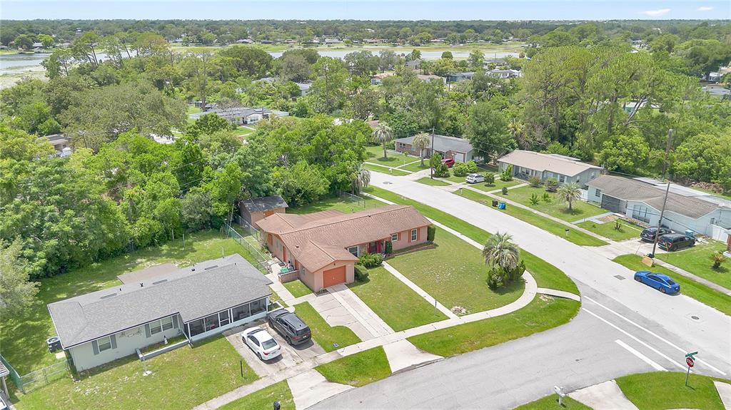An aerial view shows a residential neighborhood with two single-story houses and a nearby lake — 1140 COBBLESTONE AVENUE, DELTONA, FL