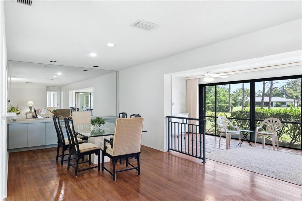 A dining area with wood floors and a mirrored wall overlooks a screened-in patio — 5451 GOLF POINTE DRIVE UNIT V-225, SARASOTA, FL