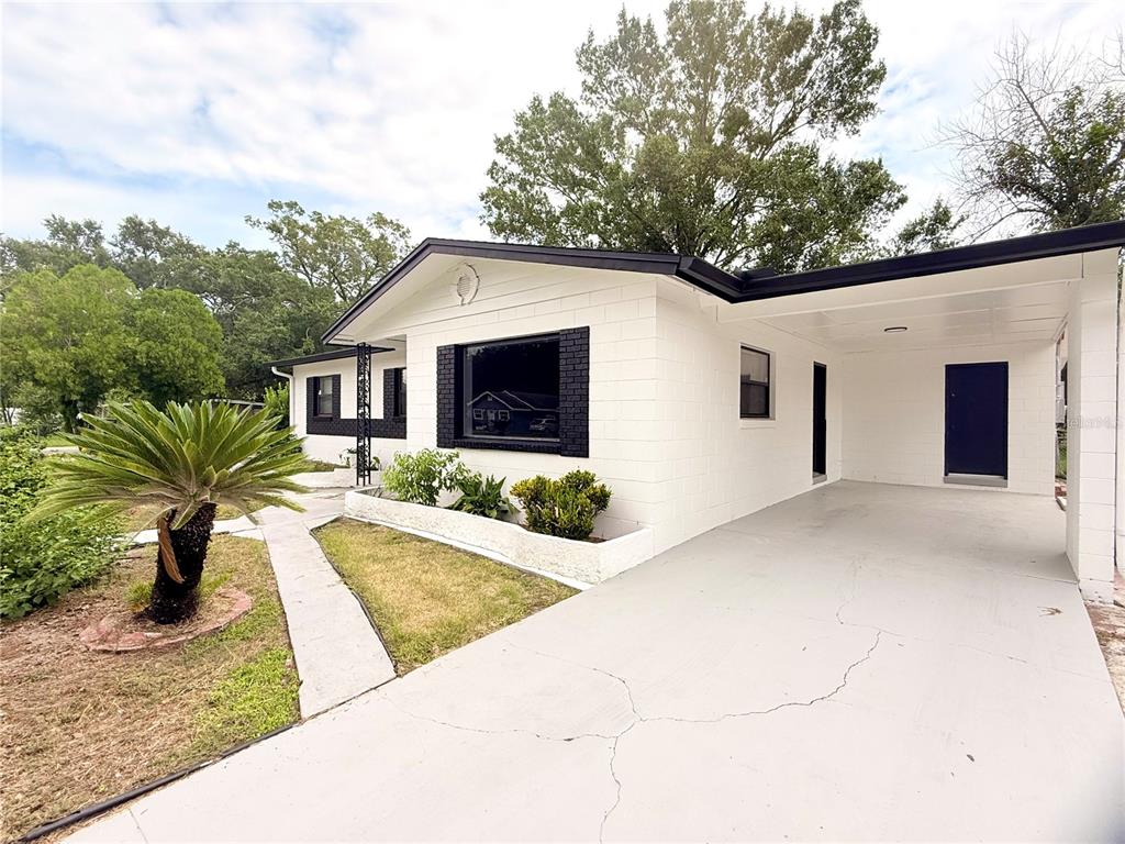 A white concrete block house features a black-trimmed window, a carport, and a palm tree — 1790 WILLIAMS MANOR AVENUE, ORLANDO, FL