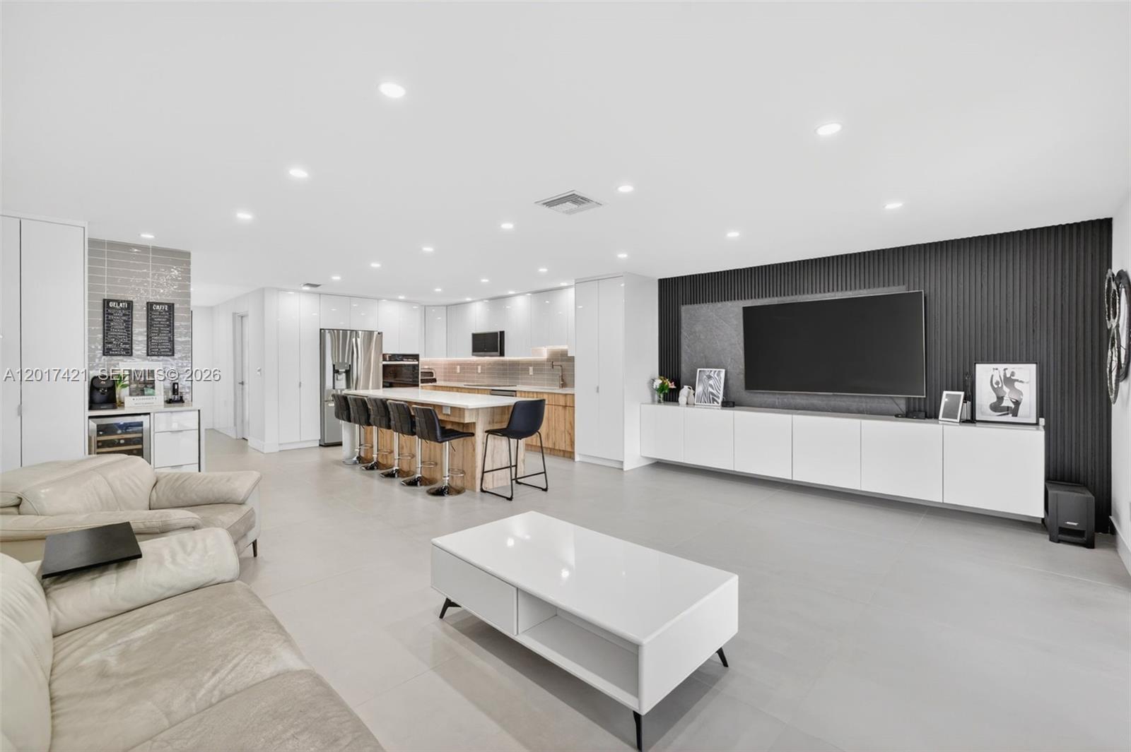 A modern open-concept living room and kitchen with white cabinetry, a large island, and television — 3848 Atlanta St, Hollywood FL 33021, HOLLYWOOD, FL