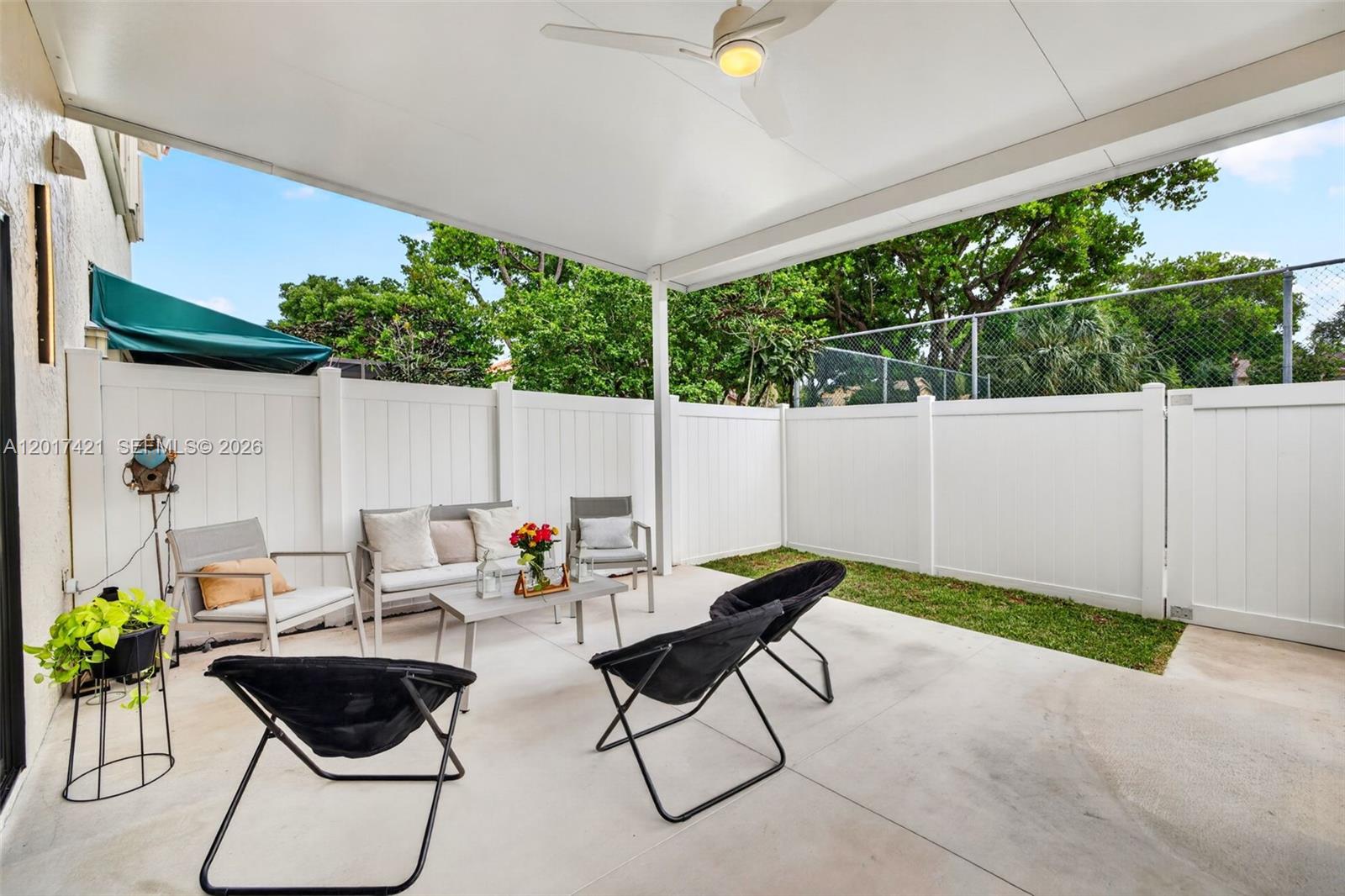 A covered patio features a concrete floor, white vinyl fencing, and outdoor furniture — 3848 Atlanta St, Hollywood FL 33021, HOLLYWOOD, FL
