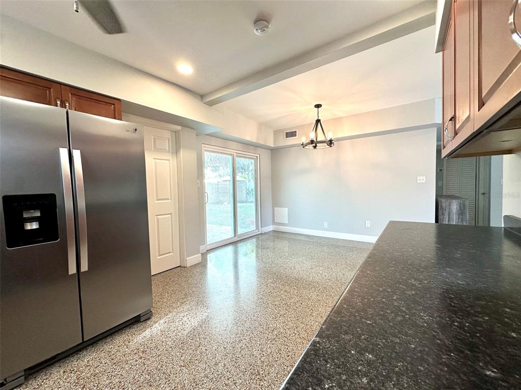 A kitchen with stainless steel appliances, dark countertops, and a dining area with sliding doors — 126 11TH AVENUE SW, LARGO, FL