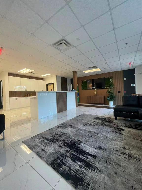 A modern office reception area features a white desk, marble floors, and wood-paneled accent walls — 7075 KINGSPOINTE PARKWAY UNIT 9, ORLANDO, FL
