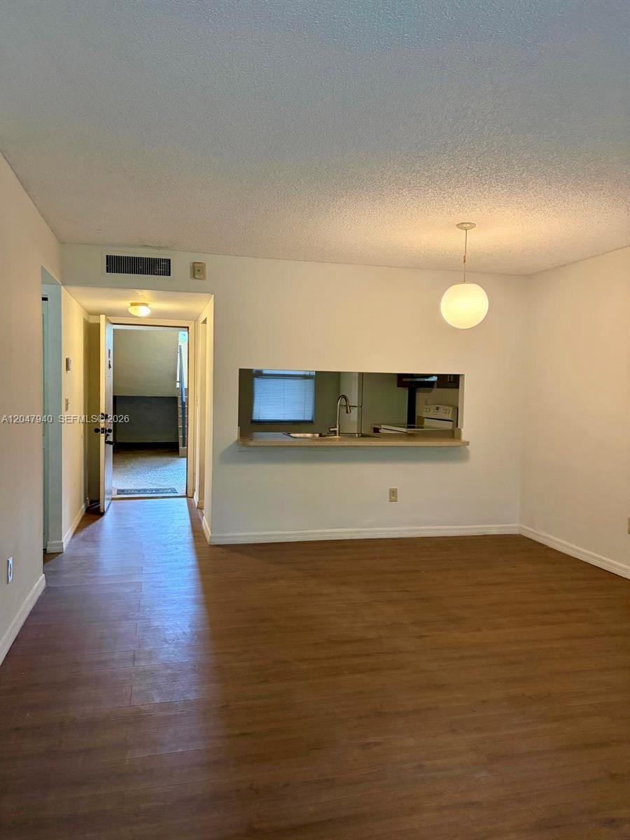 An interior view shows a dining area with wood-look flooring and a kitchen pass-through window — 100 NW 76th Ave # 2, Plantation FL 33324, PLANTATION, FL