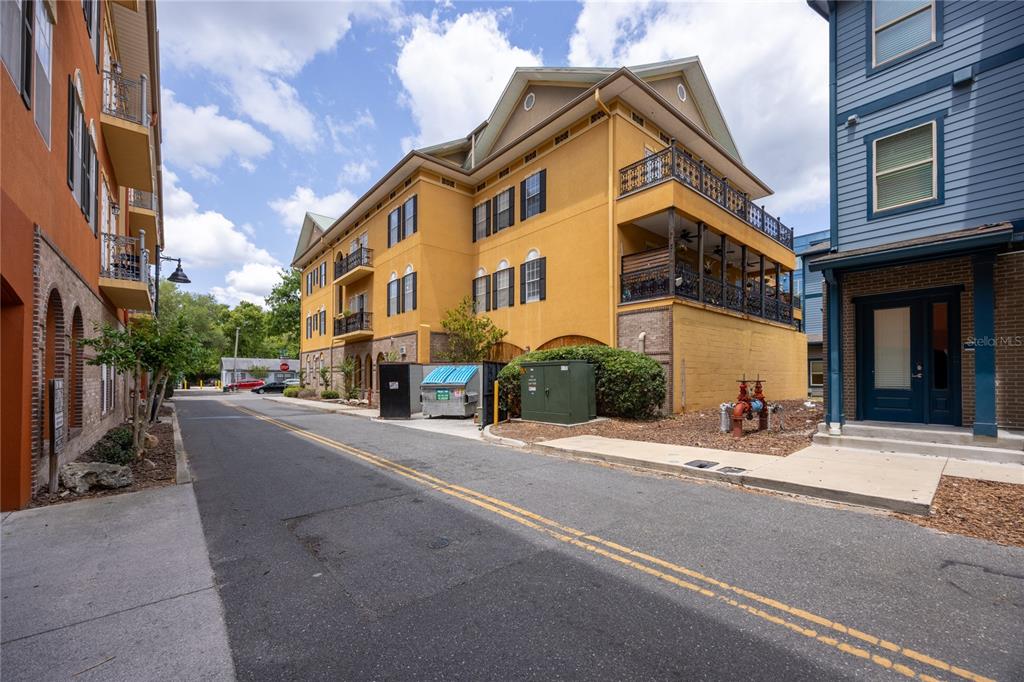 An exterior view of a yellow multi-story building featuring stacked balconies with ornate railings — 325 NW 14TH STREET UNIT 307, GAINESVILLE, FL