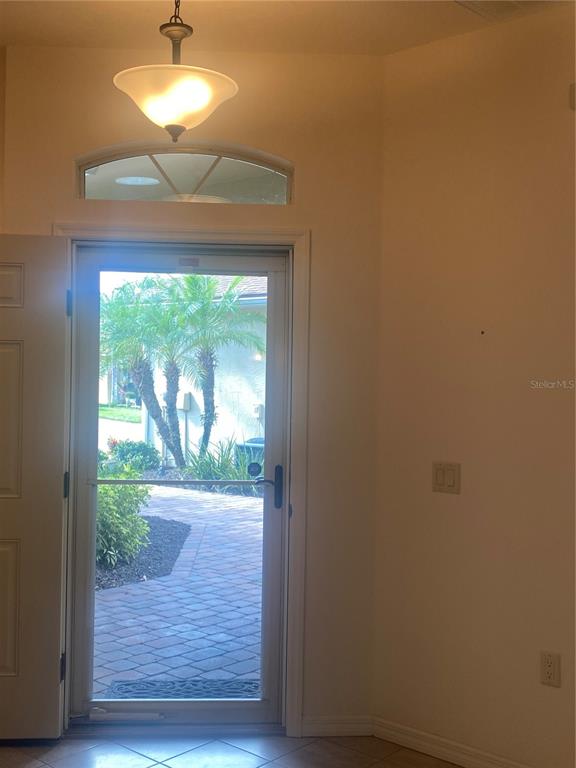 An entryway features a glass storm door, a light fixture, and a tiled floor — 1561 VIENNA SQUARE DRIVE, WINTER HAVEN, FL