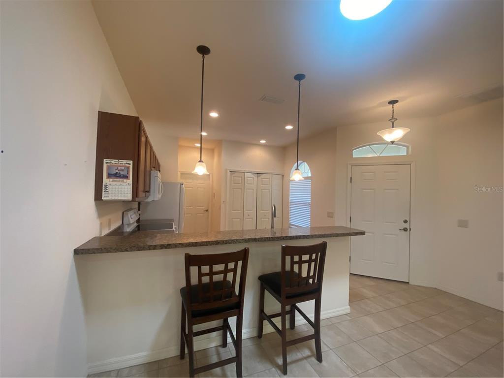 A kitchen features a breakfast bar with two wooden stools and dark wood cabinets — 1561 VIENNA SQUARE DRIVE, WINTER HAVEN, FL