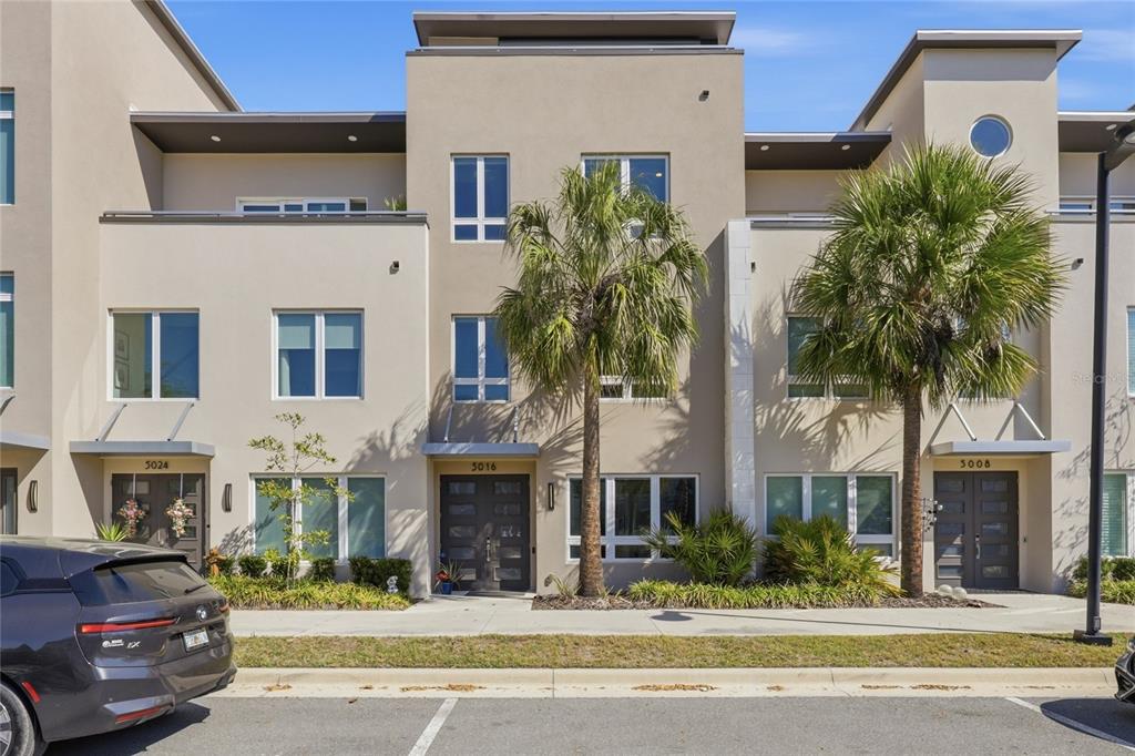 A row of modern three-story townhomes with flat roofs, palm trees, and paved parking — 5016 SW 34TH PLACE, GAINESVILLE, FL