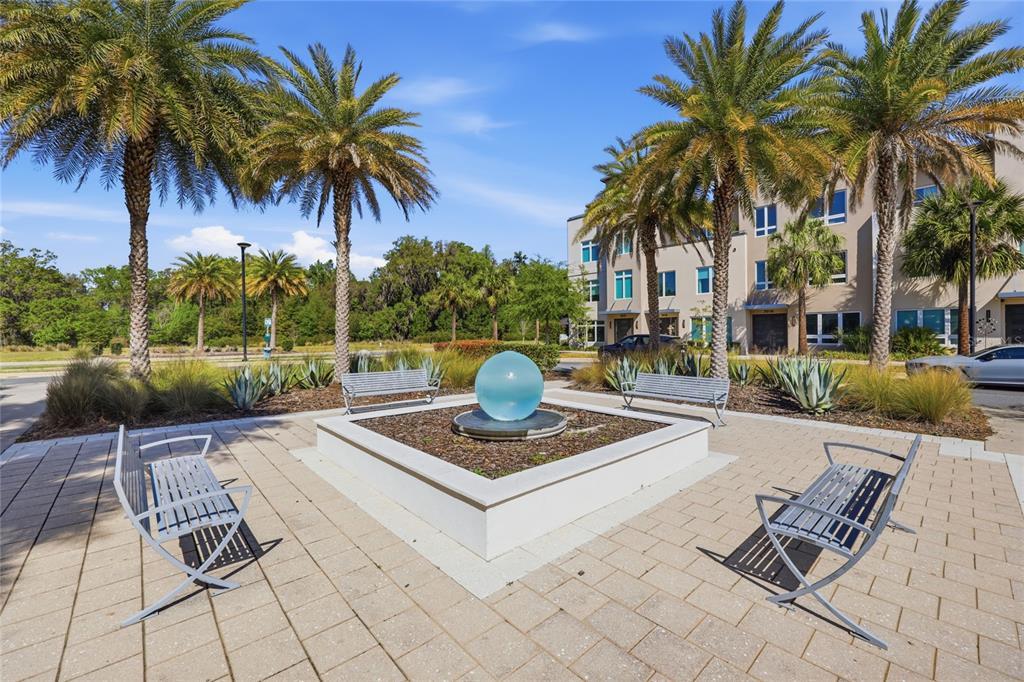 A paved courtyard features a central spherical water fountain surrounded by four metal benches — 5016 SW 34TH PLACE, GAINESVILLE, FL
