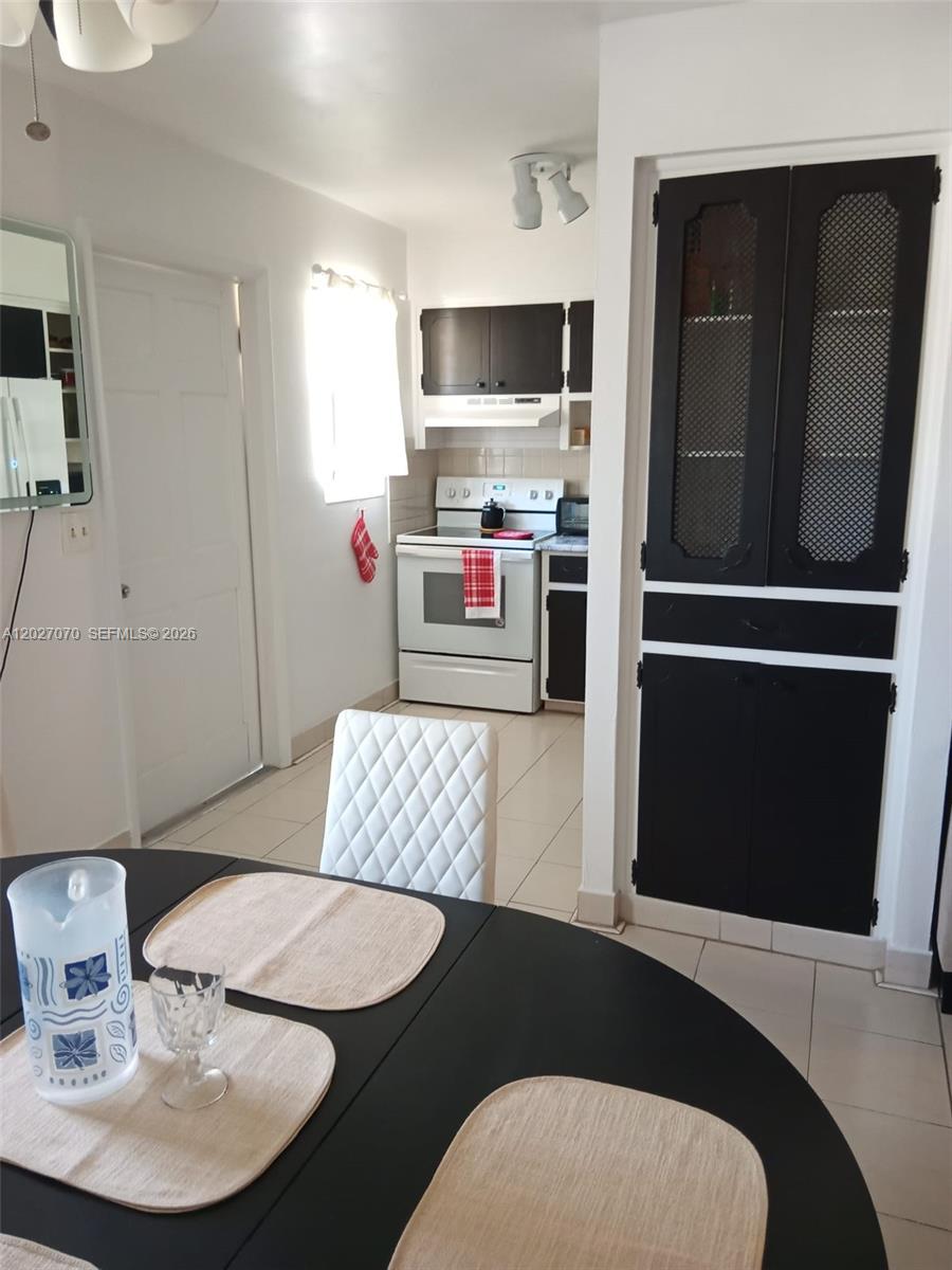 A dining area with a black table leads into a kitchen with black cabinets — 1110 N 16 Ave # 1, Hollywood FL 33020, HOLLYWOOD, FL