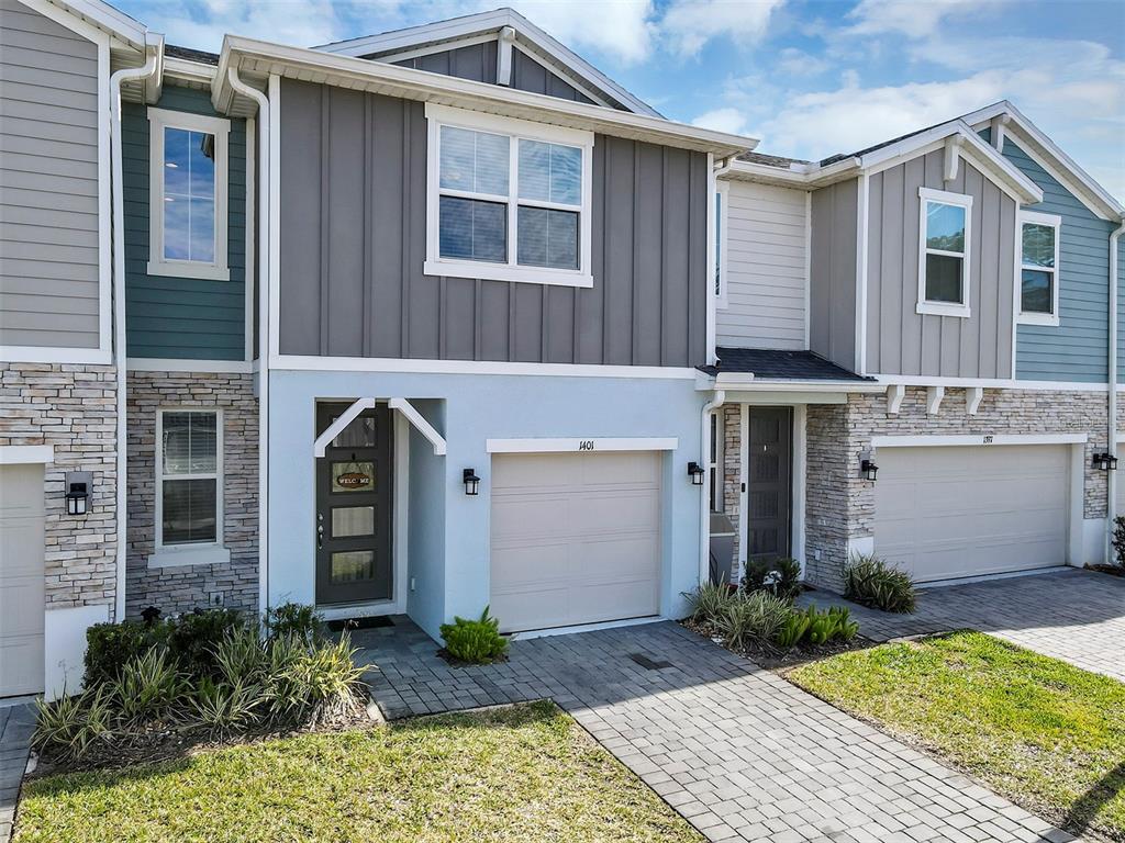 The exterior of a two-story townhouse features stone veneer, light blue siding, and a garage — 1401 CAPTIVA COVE UNIT 23, SANFORD, FL