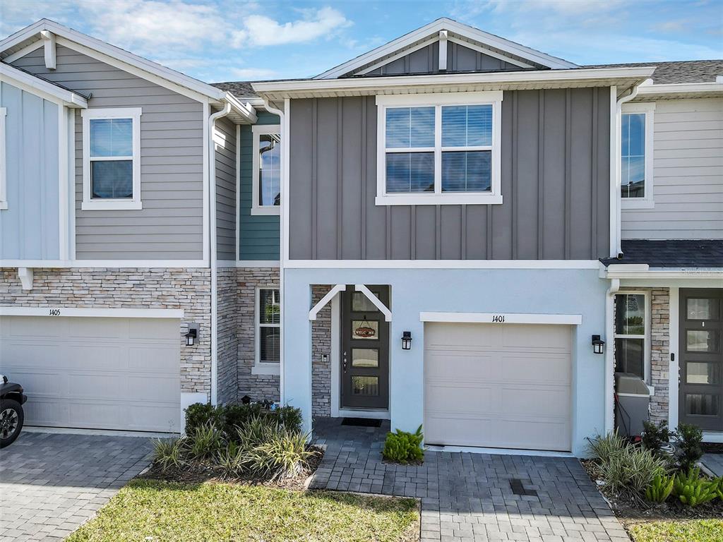 The exterior of two attached townhomes features light blue and gray siding with stone accents — 1401 CAPTIVA COVE UNIT 23, SANFORD, FL