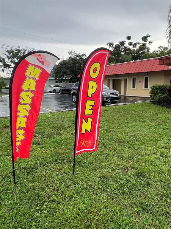 Two red feather flags advertising massage services stand on a lawn in front of a building — 5207 26TH STREET W, BRADENTON, FL