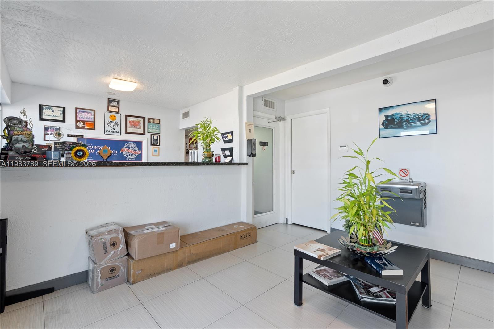 A reception area features a service counter, tiled floors, a coffee table, and wall decor — 8800 NW 27th Ave # A, Miami FL 33147, MIAMI, FL
