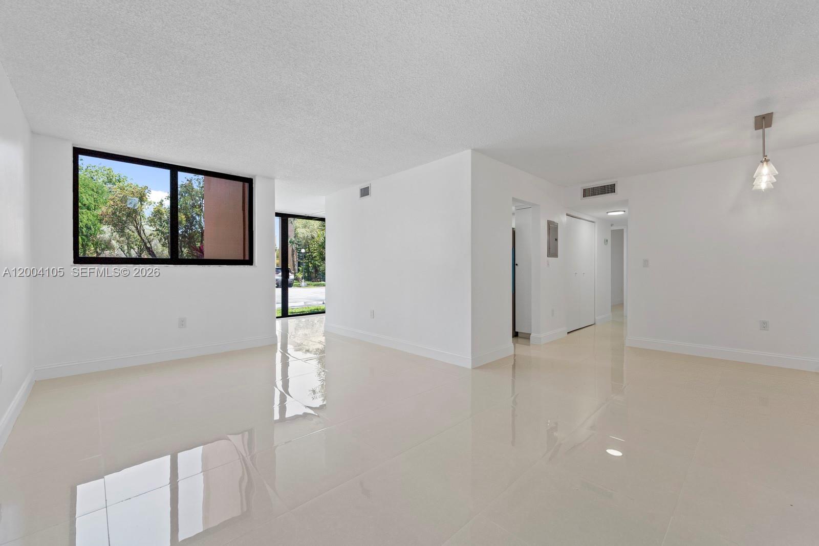An empty room with white walls, glossy tile floors, and a large window — 9440 W Flagler St # 106, Miami FL 33174, MIAMI, FL