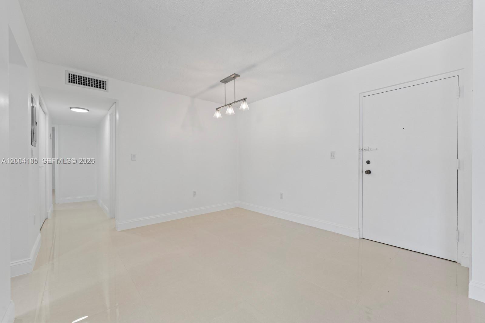 An empty room with white walls, light tile flooring, and a modern three-light pendant fixture — 9440 W Flagler St # 106, Miami FL 33174, MIAMI, FL