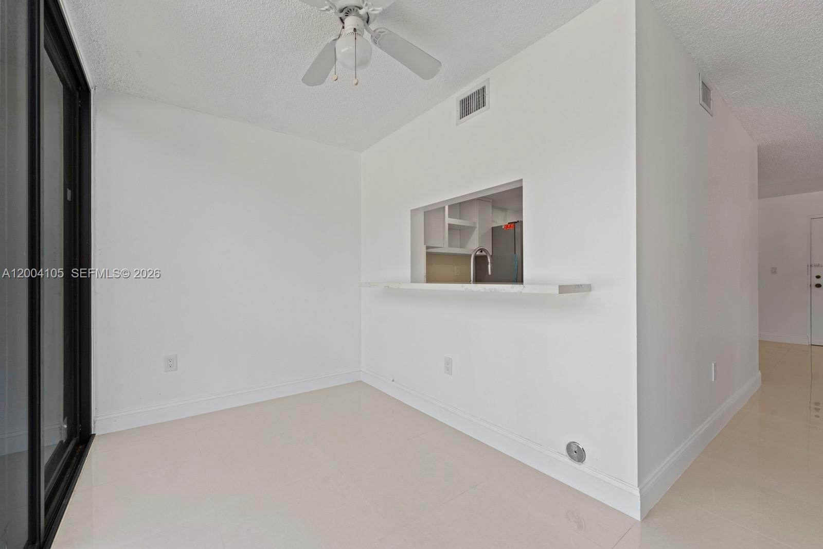 This room features white walls, tile flooring, a ceiling fan, and a kitchen pass-through window — 9440 W Flagler St # 106, Miami FL 33174, MIAMI, FL