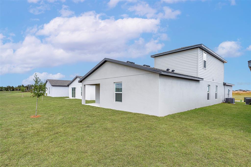 The exterior of a light-colored, two-story suburban house sits on a large, grassy lot — 5215 CAP ROAD, BROOKSVILLE, FL