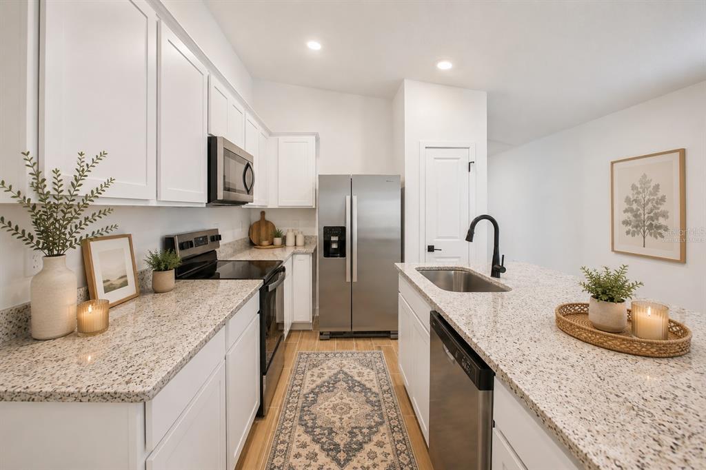A kitchen with white cabinets, granite countertops, stainless steel appliances, and a patterned runner rug — 5215 CAP ROAD, BROOKSVILLE, FL
